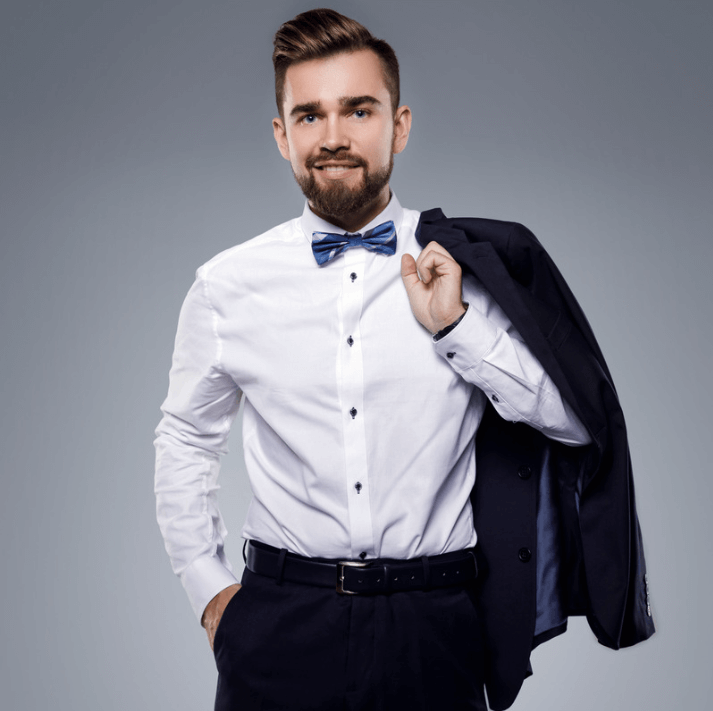 Muž v bílém košili a modré kravaty drží sako, usmívá se a působí stylově.